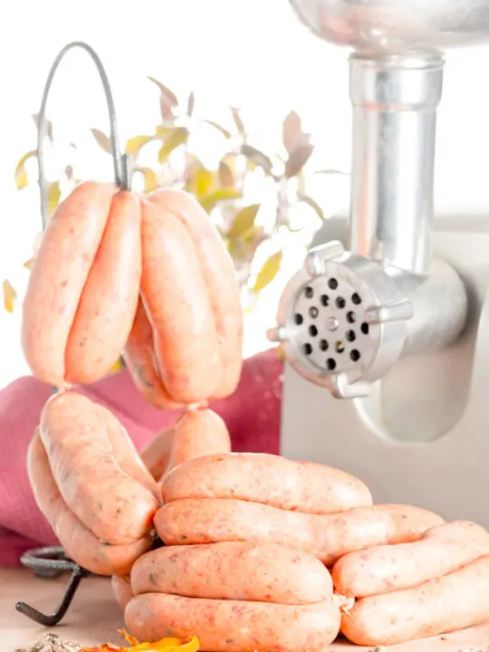 Homemade uncooked pork sausages in a scene with a meat grinder