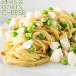 Pesto spaghetti is given a new breath of life with some peas, goats cheese and some extra pine nuts, to make a quick pasta dinner. #italianfood #italianrecipes