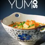 Portrait image of a Tom Yum Soup served in an Asian style soup bowl decorated with a blue flower in a dark setting with text