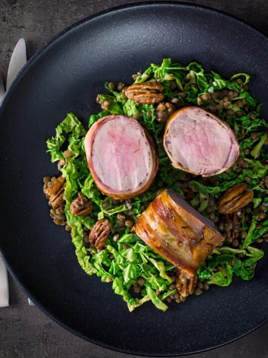 This simple bacon wrapped pork tenderloin recipe is served with a fantastic lentil, pecan nut and cabbage side dish dressed with a mustard dressing.