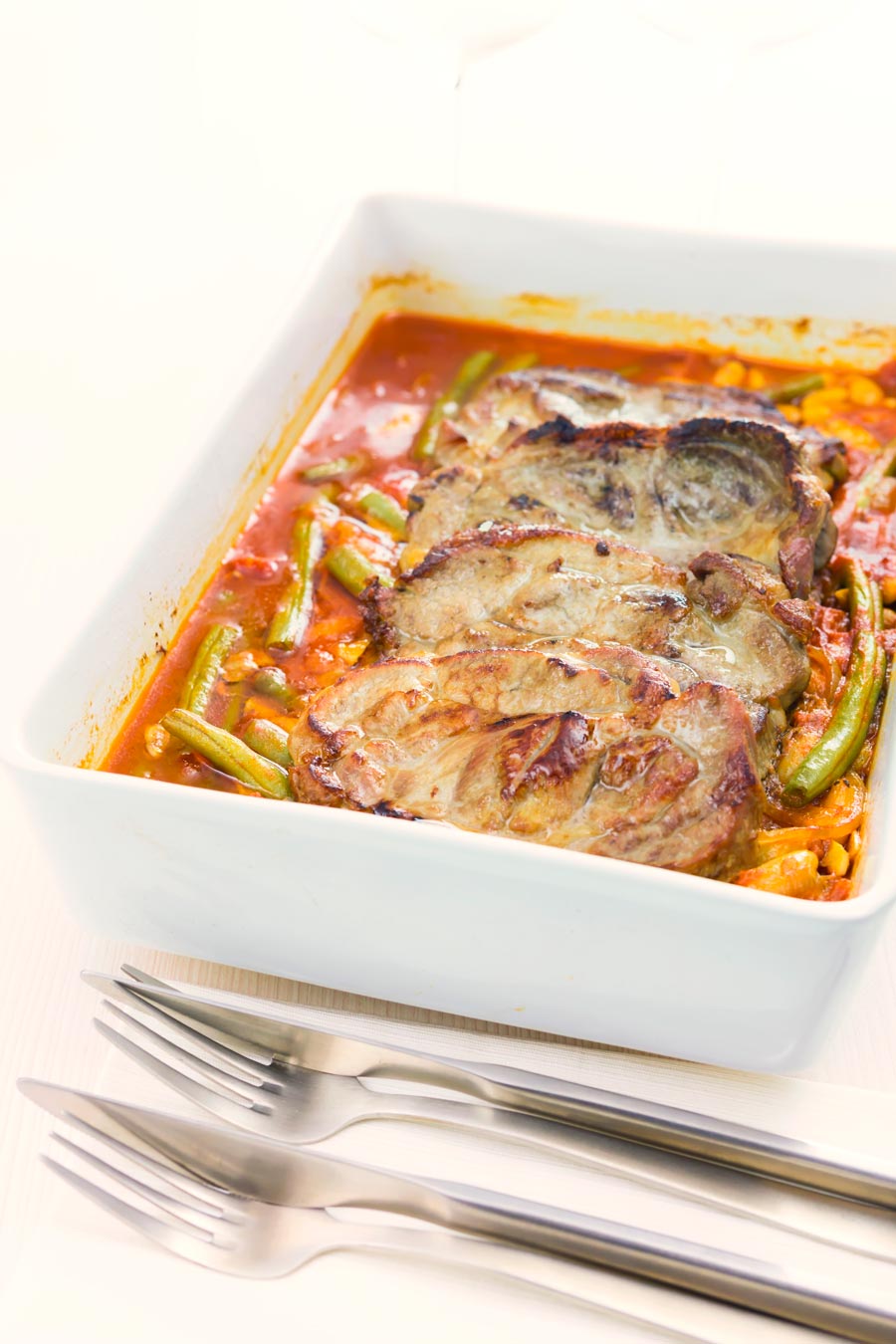 Roast pork chops are always fab and these boneless pork blade or Boston butt chops are roasted on a bed of green beans and white beans in a tomato sauce.