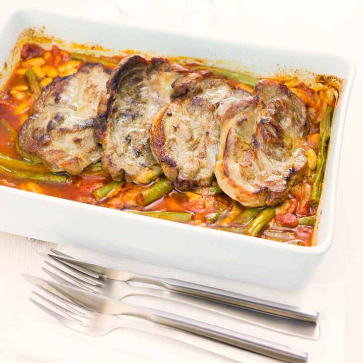 Roast pork chops are always fab and these boneless pork blade or Boston butt chops are roasted on a bed of green beans and white beans in a tomato sauce.