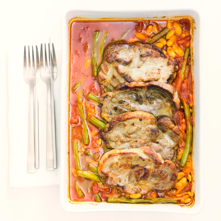 Roast pork chops are always fab and these boneless pork blade or Boston butt chops are roasted on a bed of green beans and white beans in a tomato sauce.