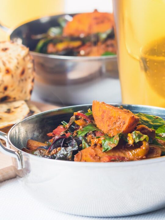 Portrait image of Indian Chapati flatbreads with a curry and beer out of focus in the background.
