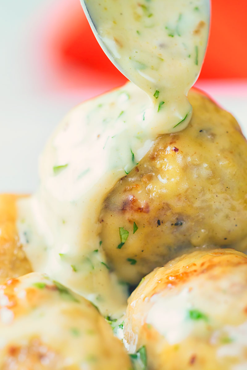 Close up portrait image of a creamy honey and mustard sauce poured over chicken meatballs