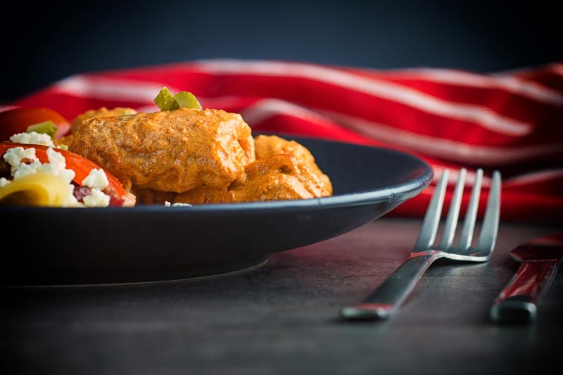 Landscape image of catfish paprikash with tomatoes and a pasta side dish