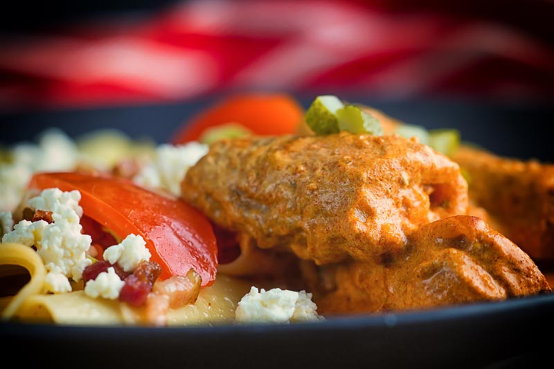 Close up landscape image of catfish paprikash with tomatoes and a pasta side dish