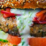 Portrait close up detail image of an Indian inspired spicy lamb burger with a red onion chutney detail