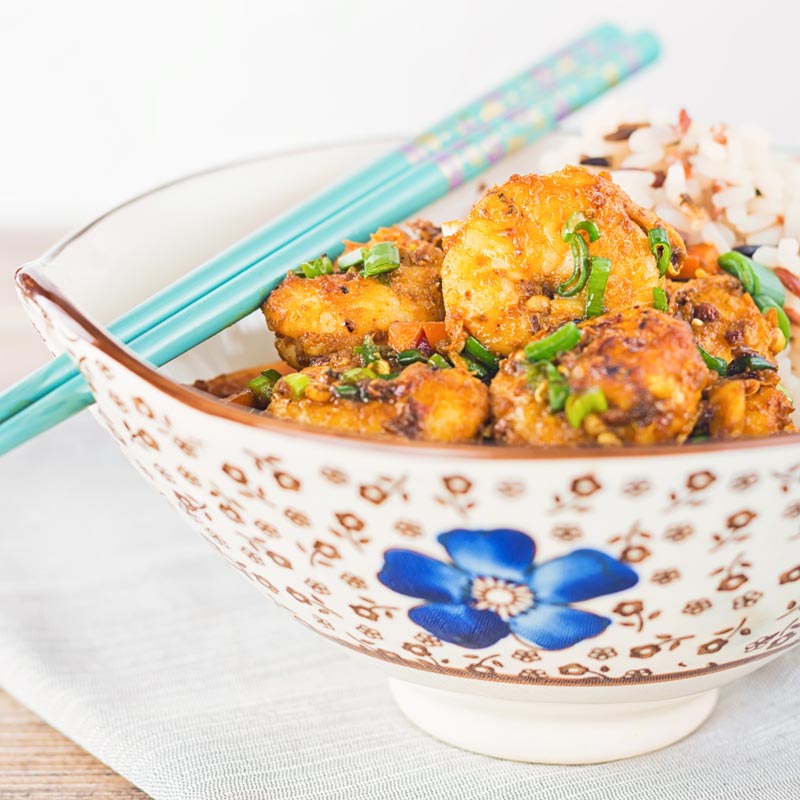 Square image of shrimp stir fry in an Asian style bowl with a blue flower