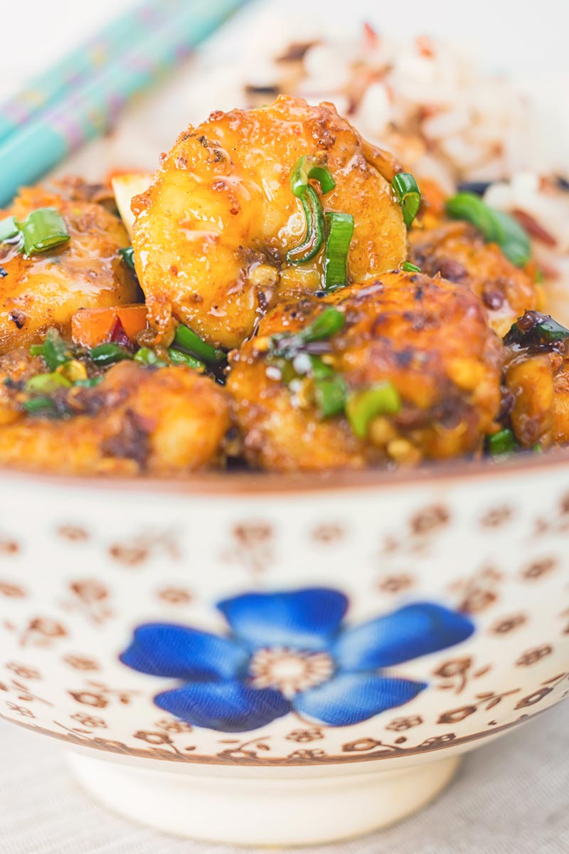 Close up of shrimp stir fry in an Asian style bowl with a blue flower