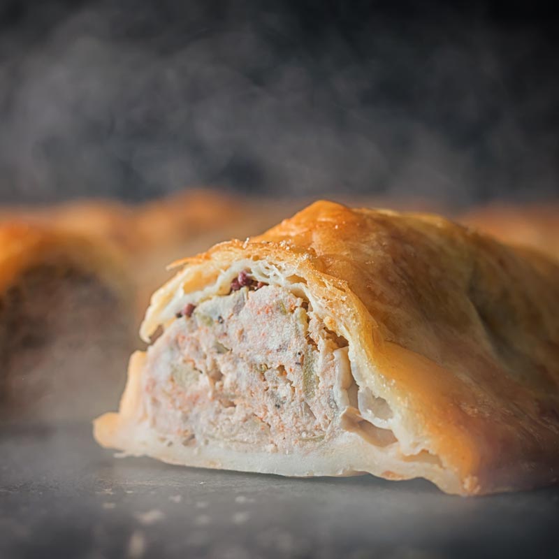 Square close up image of the interior of a shortcrust pastry wrapped sausage roll