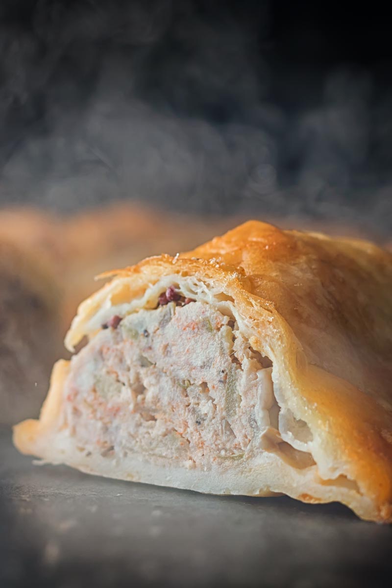 Tall close up image of the interior of a shortcrust pastry wrapped sausage roll