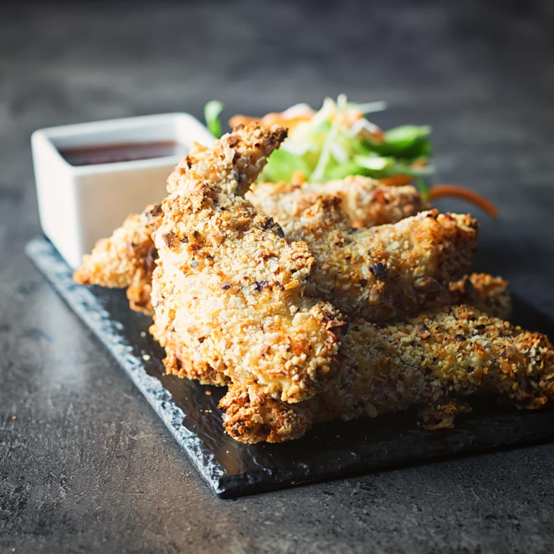 Baked Crispy Chicken Tenders on a slate against a dark backdrop