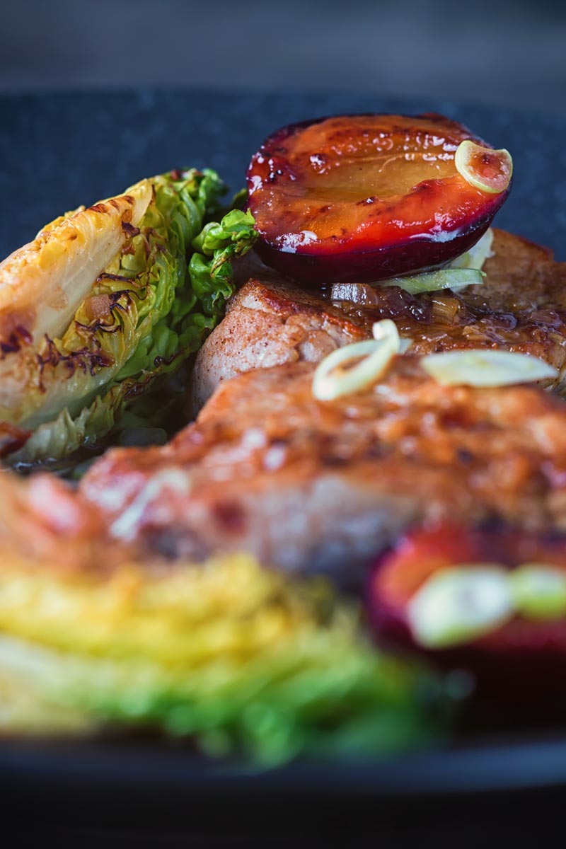 Tall image of a seared plum on some Chinese pork tenderloin.