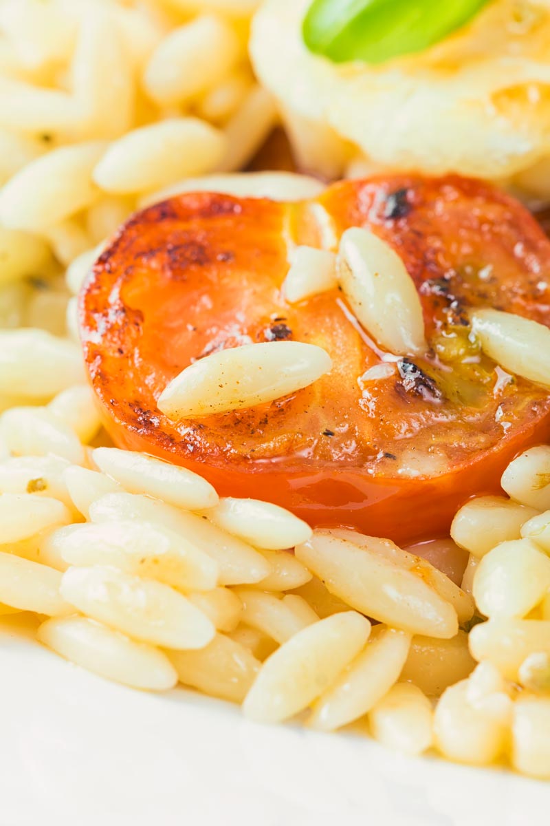Orzo pasta grains on a seared tomato in a orzo salad