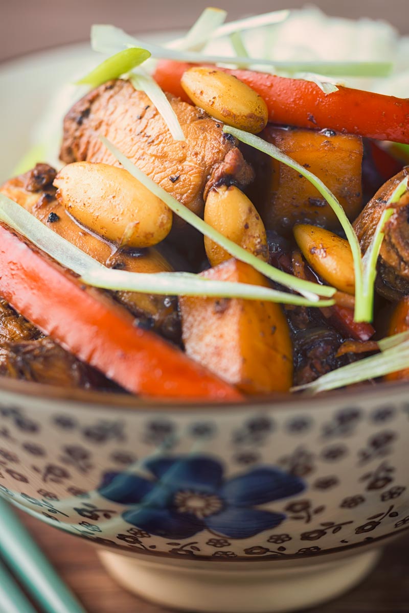 Close up tall image of stir fried mango chicken with almonds, red pepper and spring onions