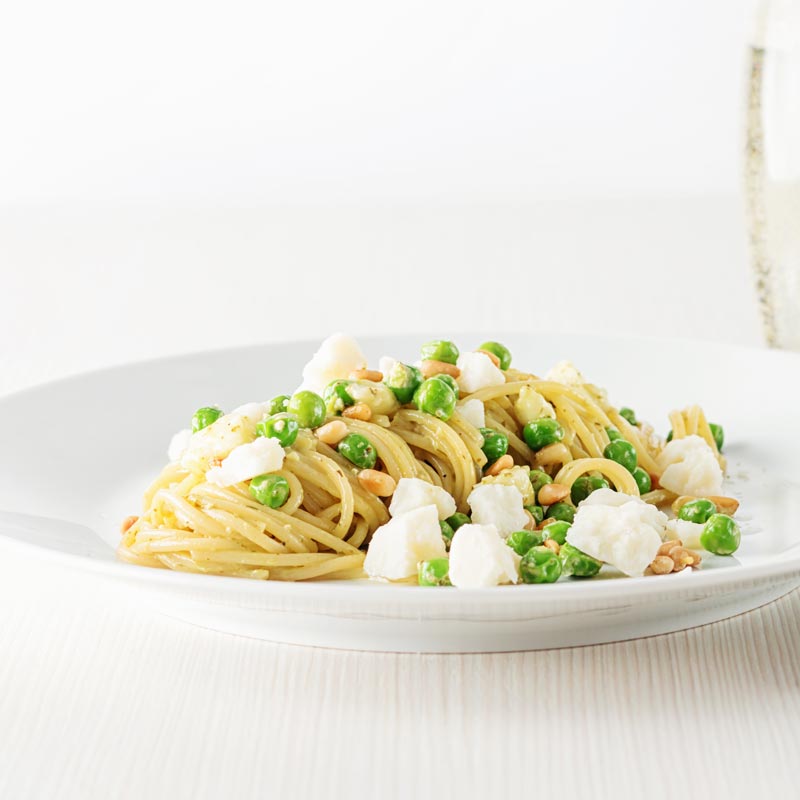 Pesto spaghetti is given a new breath of life with some peas, goats cheese and some extra pine nuts, to make a quick pasta dinner.