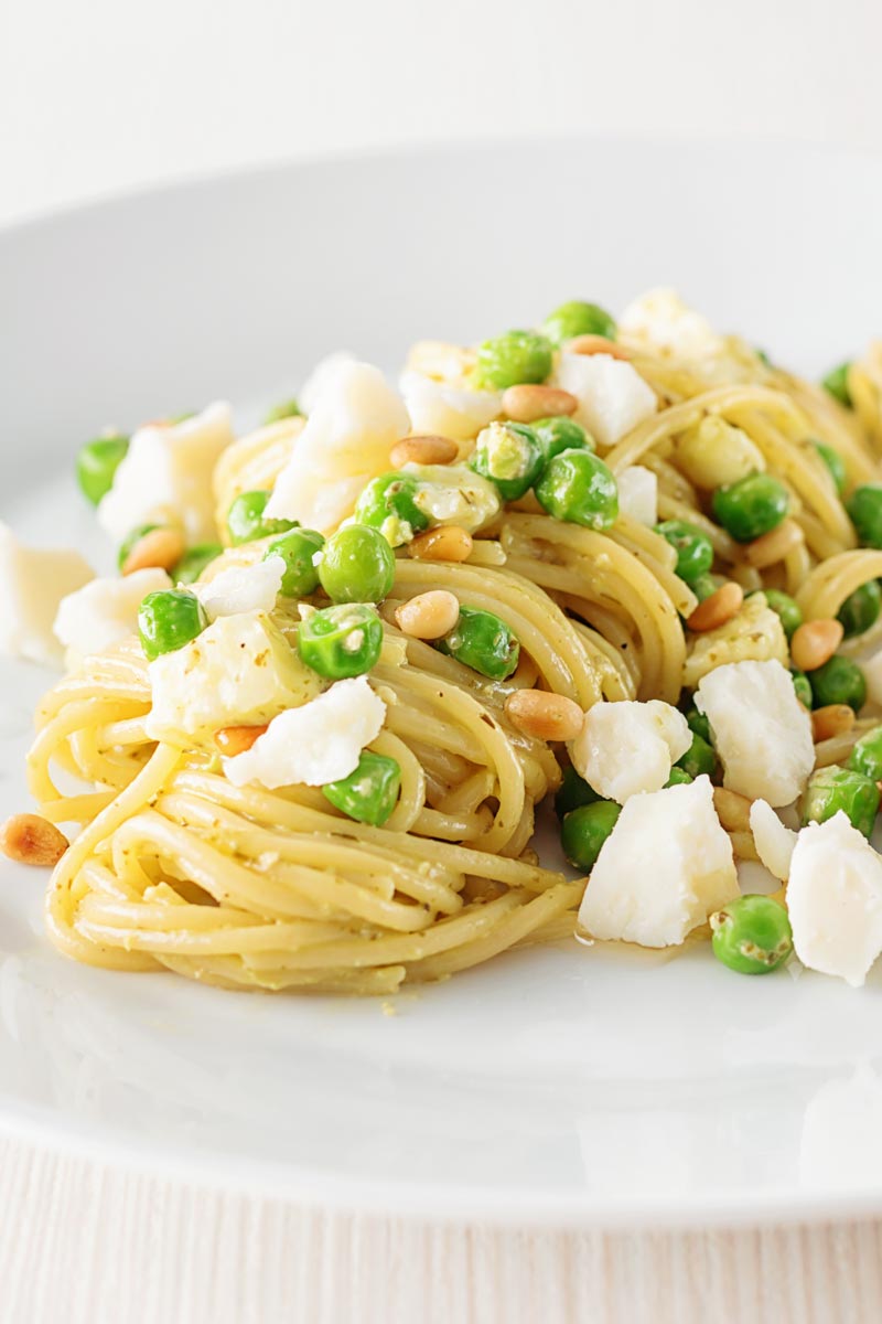 Pesto spaghetti is given a new breath of life with some peas, goats cheese and some extra pine nuts, to make a quick pasta dinner.