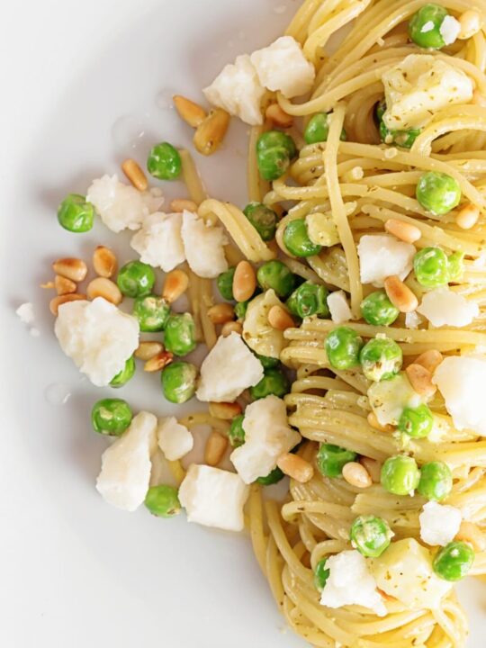 Pesto spaghetti is given a new breath of life with some peas, goats cheese and some extra pine nuts, to make a quick pasta dinner.