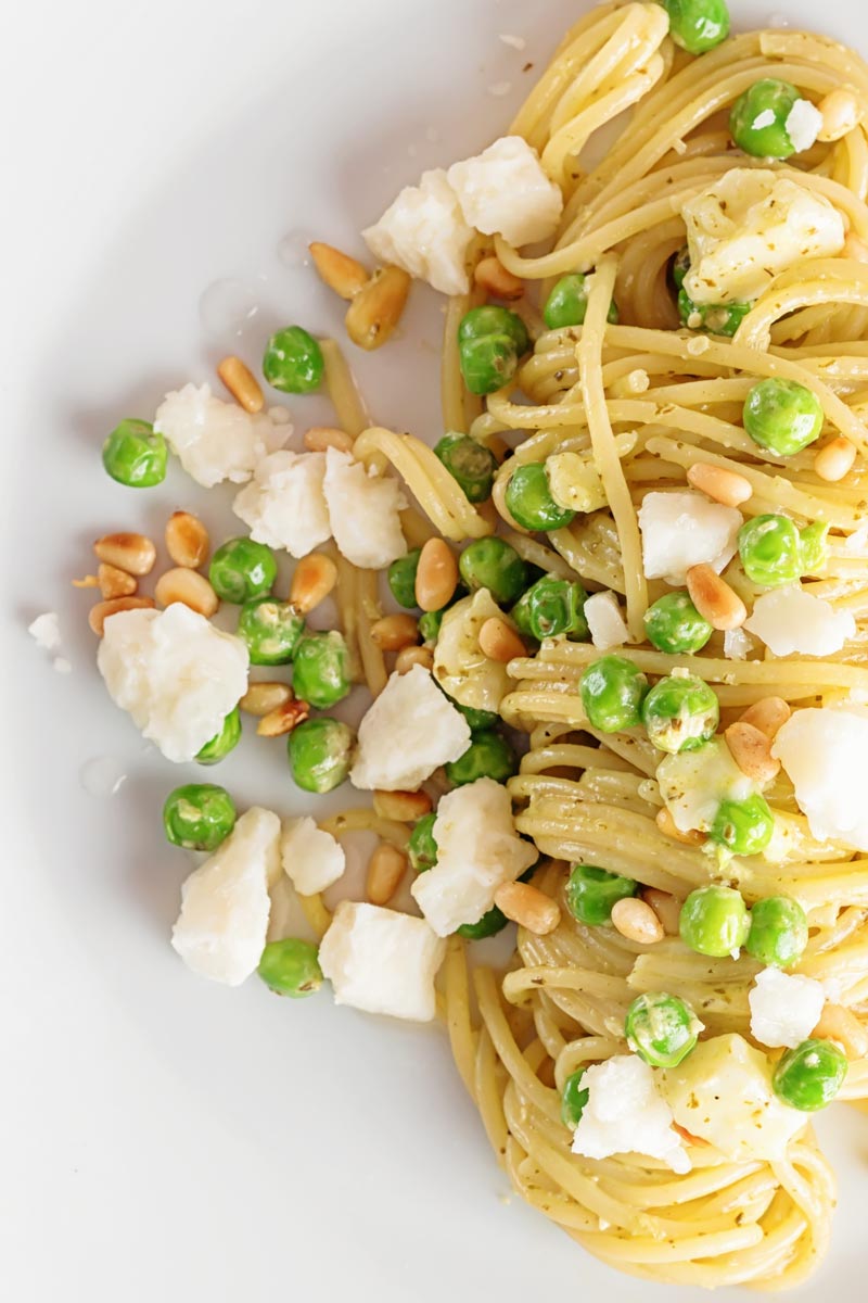 Pesto spaghetti is given a new breath of life with some peas, goats cheese and some extra pine nuts, to make a quick pasta dinner.