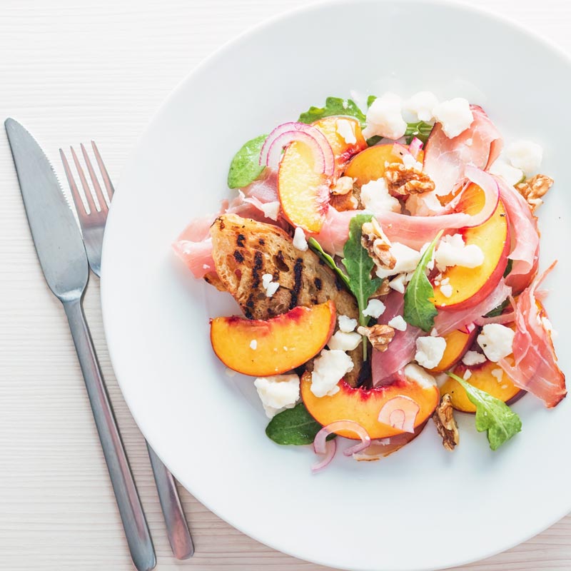 Square image of a ham and cheese salad with pickled peaches taken from above