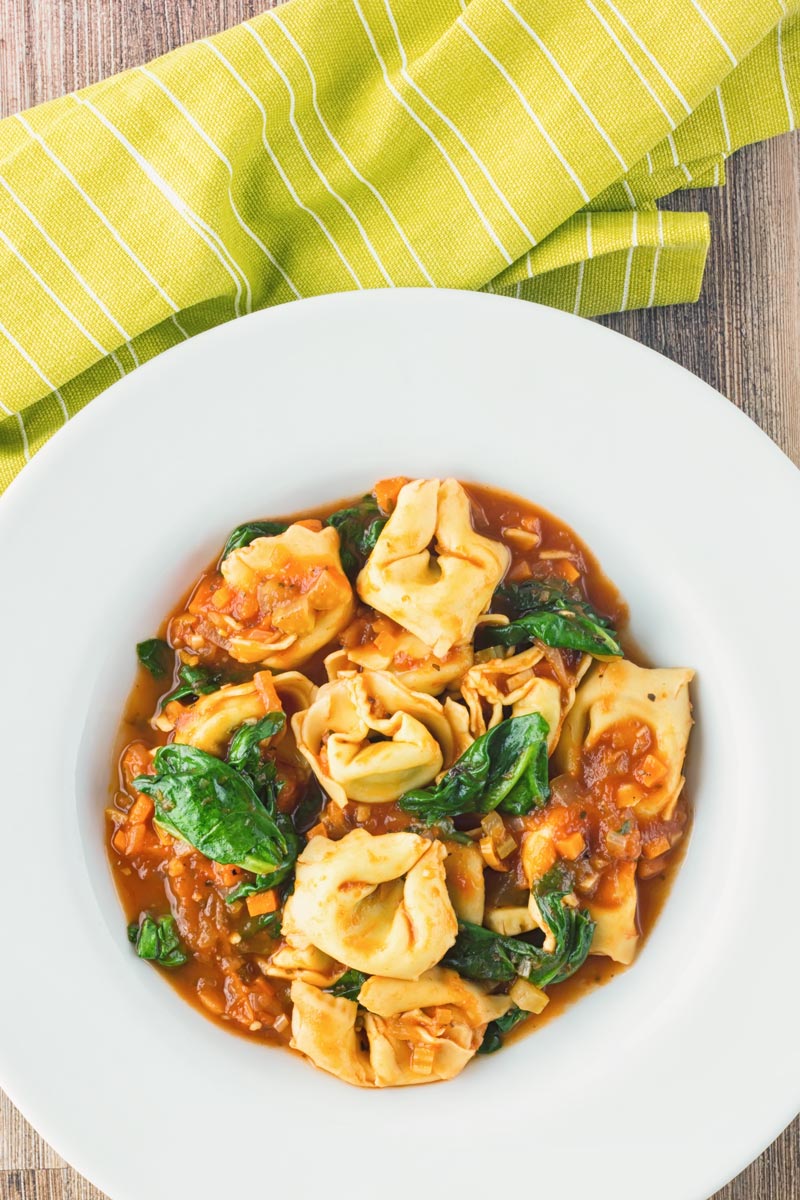 Tortellini soup in a white bowl taken from above