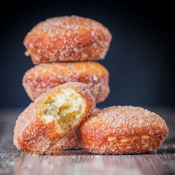 Cinnamon sugar coated donuts with a bite out of one cooked from a basic donut recipe