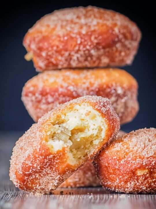 Portrait Image of cinnamon sugar coated donuts with a bite out of one cooked from a basic donut recipe
