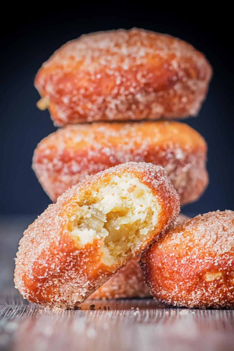 Portrait Image of cinnamon sugar coated donuts with a bite out of one cooked from a basic donut recipe