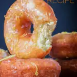 Portrait Image of lemon glazed ring donuts with a bite out of one cooked from a basic donut recipe with text