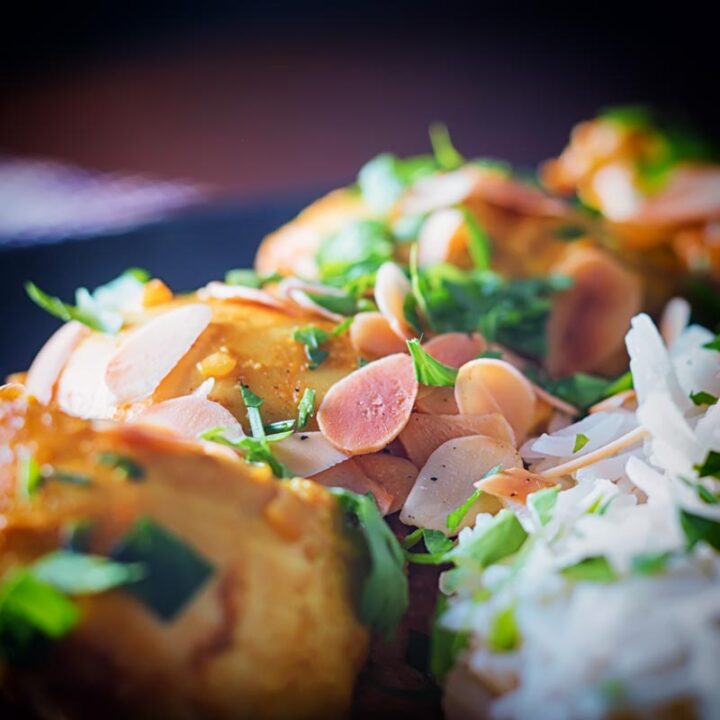 quadrado extremo perto de um frango pasanda curry com amêndoas em flocos e coentro