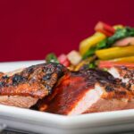 Vertical image of duck with plum sauce against a red background