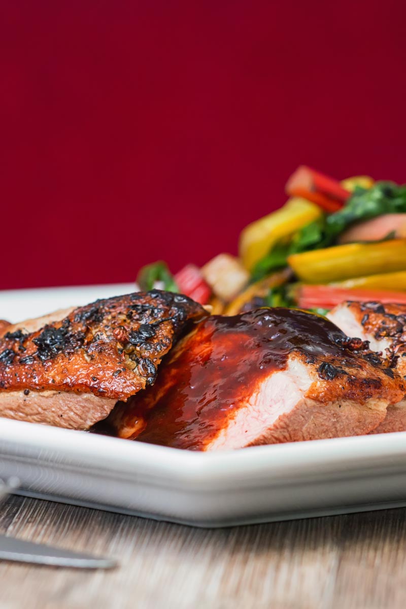 Portrait image of a rosy pink duck breast with a plum sauce