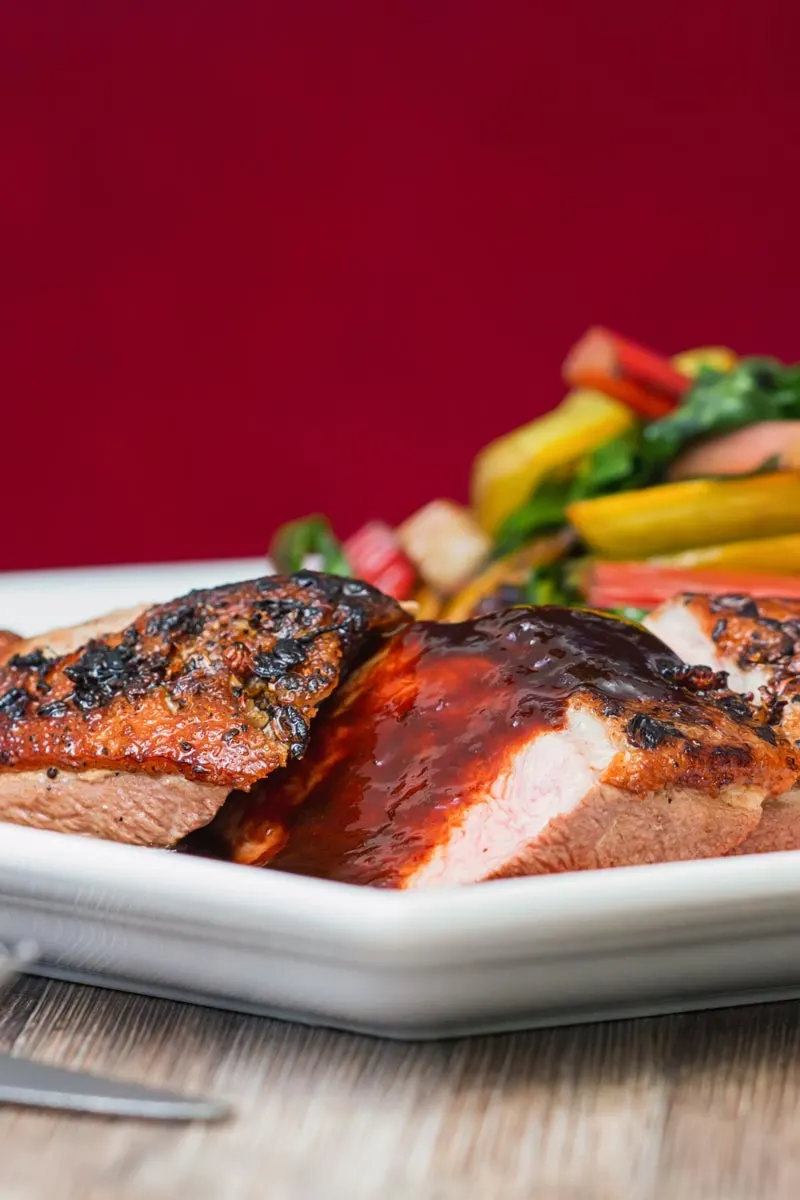 Portrait image of a rosy pink duck breast with a plum sauce