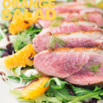 Portrait overhead image of a fennel and orange salad served with a sliced rosy pink duck breast served on a white plate with text