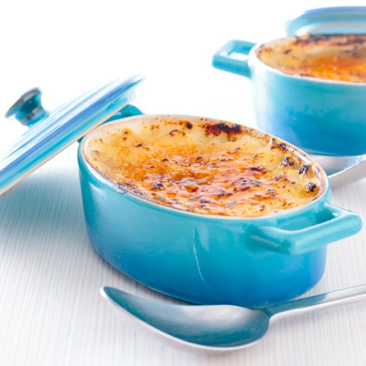 Square image of an individual instant pot rice pudding cooked in blue serving pots with a brulee topping