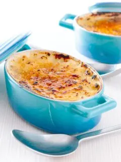 Tall close up image of an individual instant pot rice pudding cooked in blue serving pots with a brulee topping