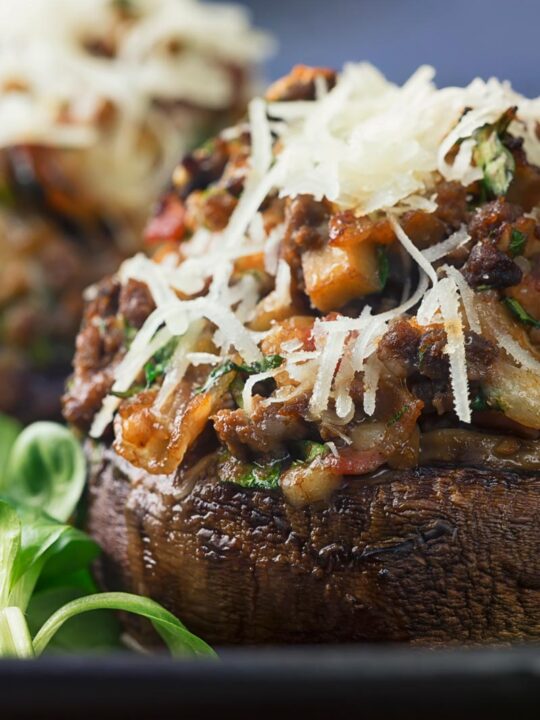 Close up tall image of a minced beef stuffed mushroom topped with Parmesan cheese