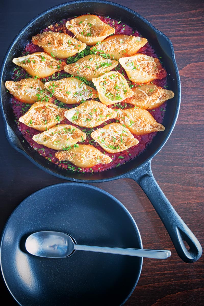 Portrait overhead image of Goats Cheese Stuffed Pasta Shells cooked and served in a cast iron skillet