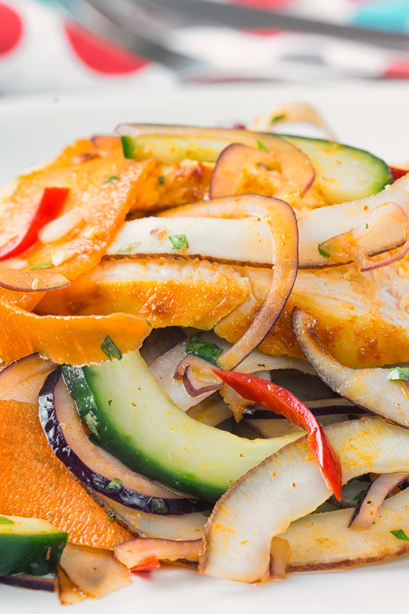 Portrait close up image of a Thai salad featuring chicken breast, fresh coconut, carrots and red onion