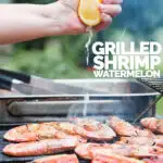 Portrait image of fresh lemon being squeezed over BBQ prawns or shrimp on a BBQ with watermelon with text