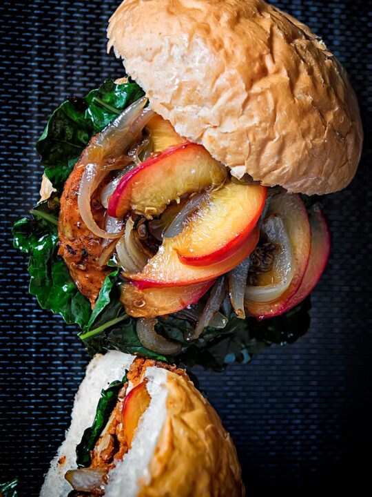 Portrait overhead image of a spicy veggie burger topped with an onion and peach chutney served on a bun