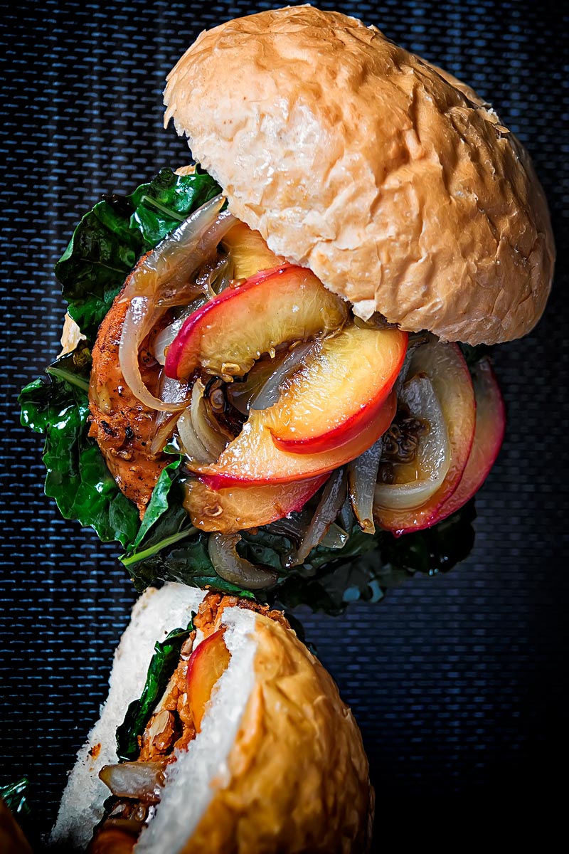 Portrait overhead image of a spicy veggie burger topped with an onion and peach chutney served on a bun