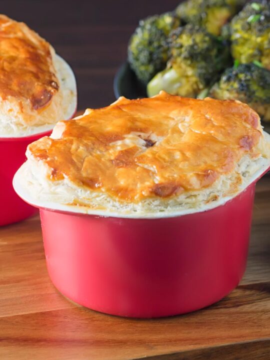 Portrait image of a beef and ale pie served pot pie style in a red pot