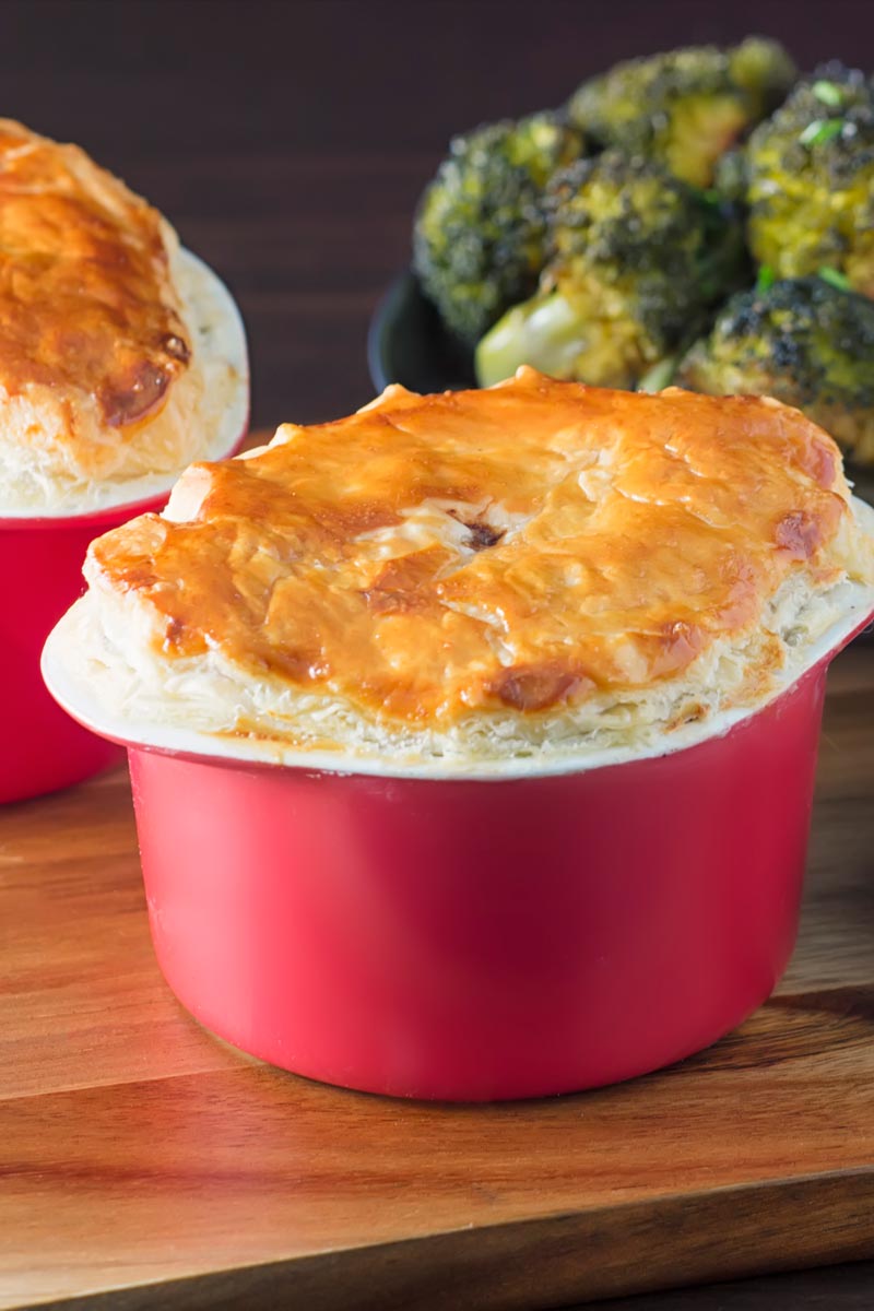 Portrait image of a beef and ale pie served pot pie style in a red pot