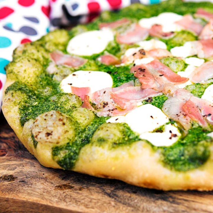 Square image of a Rocket Pesto Pizza with goats cheese and bacon