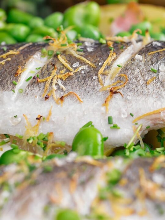 Portrait close up image of baked sea bass fillets slashed and scattered with lemon zest