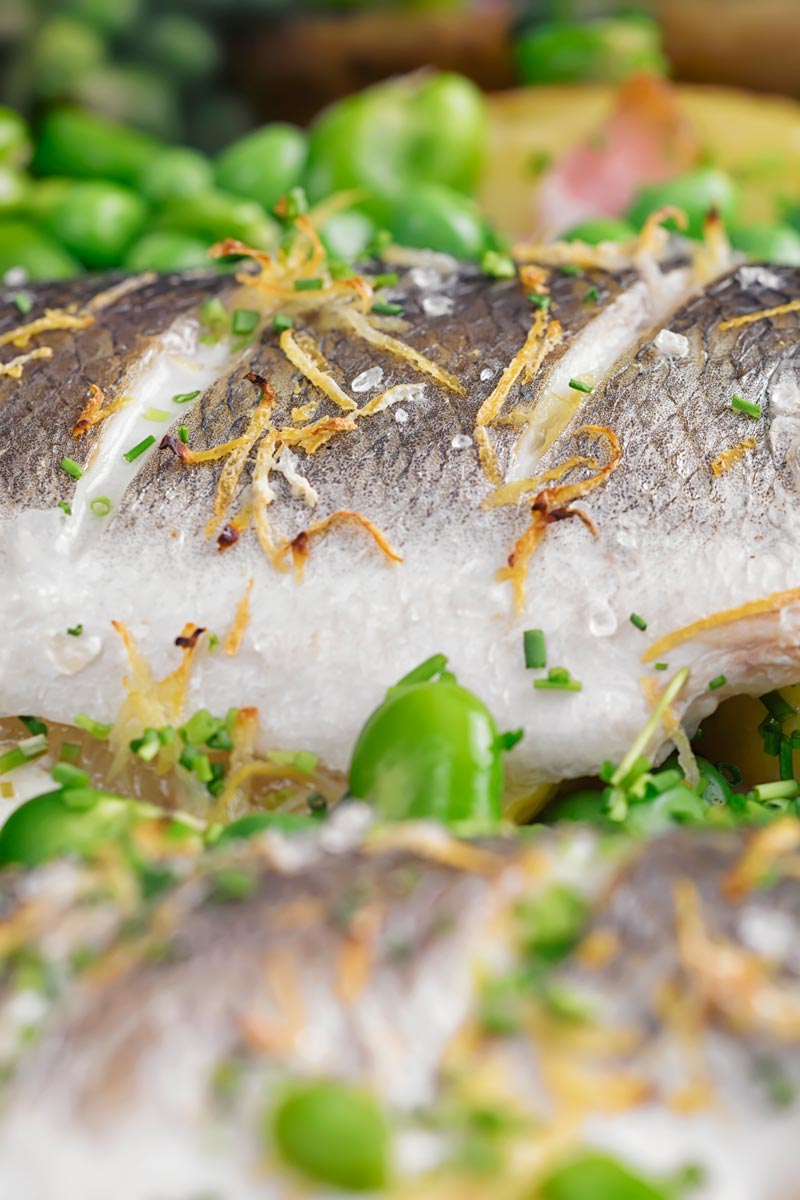 Portrait close up image of baked sea bass fillets slashed and scattered with lemon zest
