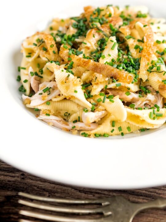 Portrait image of sage and onion chicken pasta served in a white shallow bowl