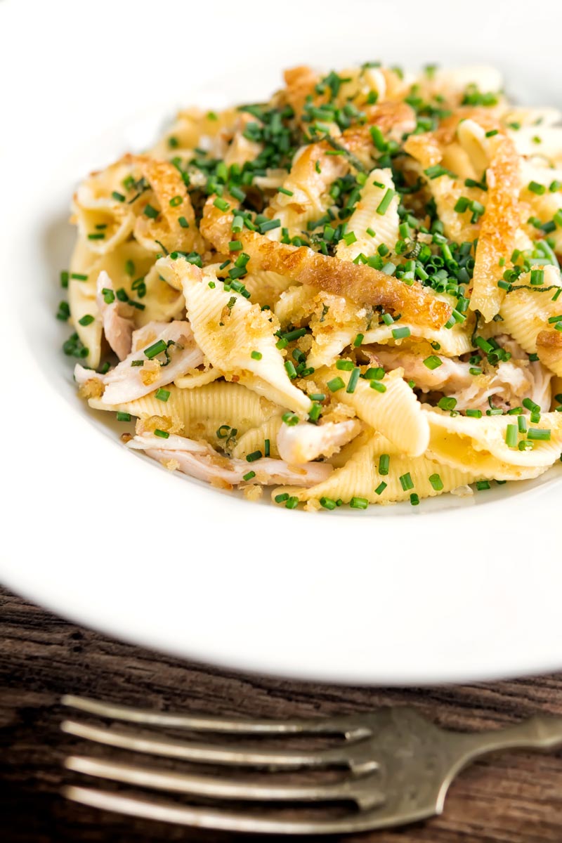 Portrait image of sage and onion chicken pasta served in a white shallow bowl
